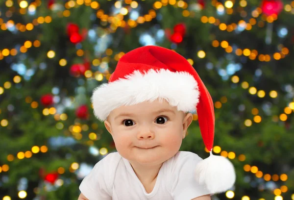 Ребенок в шляпе санта над огнями рождественской елки — стоковое фото