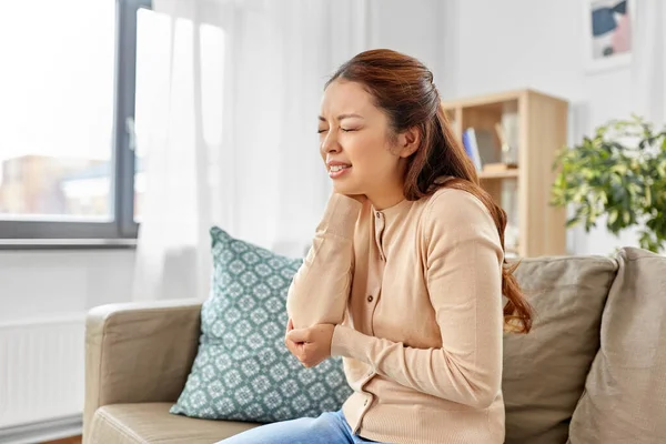 Азиатская женщина страдает от боли в руке в домашних условиях — стоковое фото