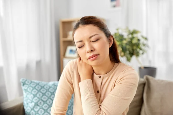 Asiatisk kvinna som lider av värk i nacken hemma — Stockfoto