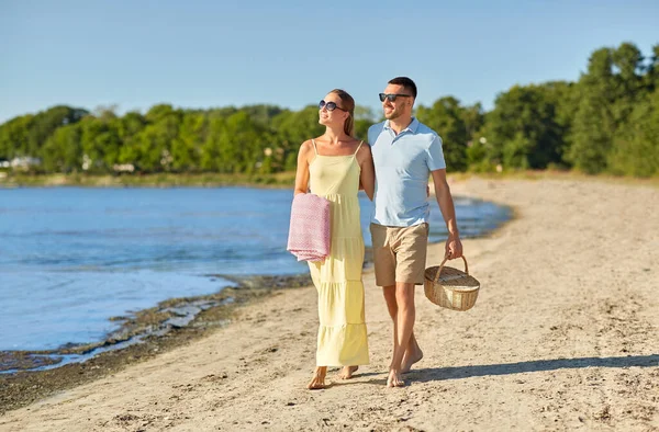 Szczęśliwa para z koszykiem piknikowym spacerująca po plaży — Zdjęcie stockowe