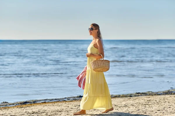 Gelukkig vrouw met picknick mand wandelen langs het strand — Stockfoto