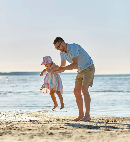 Lykkelig far som leker med en liten datter på stranden – stockfoto