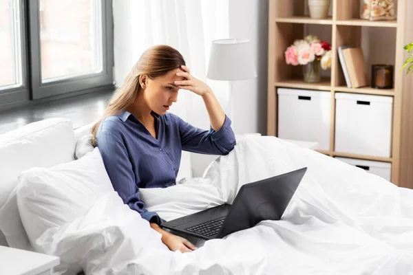 Mujer joven estresada con el ordenador portátil en la cama en casa — Foto de Stock