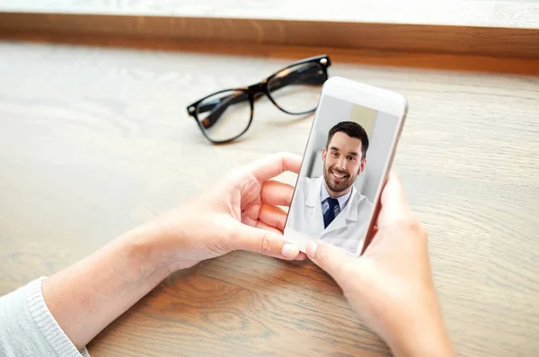 Hands of woman holding phone with doctor on screen — Stock Photo, Image