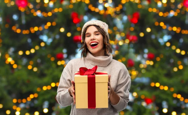 Şapkalı mutlu genç bir kadın Noel hediyesi taşıyor. — Stok fotoğraf