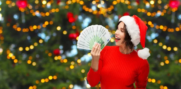 Donna felice in cappello di Babbo Natale con i soldi a Natale — Foto Stock