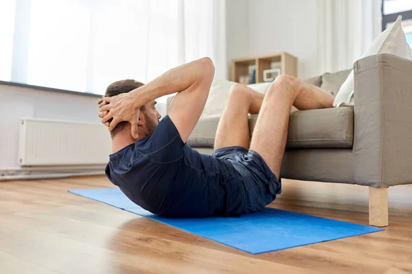 Hombre haciendo ejercicios abdominales en casa —  Fotos de Stock