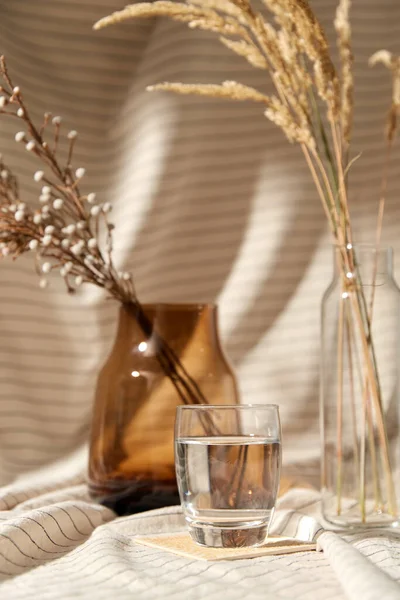 Стакан воды, декоративные сушеные цветы в вазах — стоковое фото