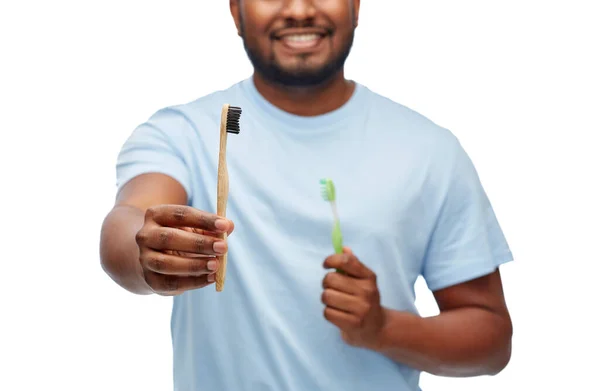 Man die houten en plastic tandenborstels met elkaar vergelijkt — Stockfoto