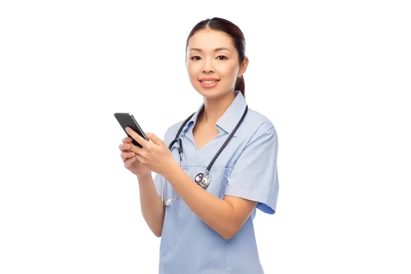 Glad asiatisk kvinnlig läkare eller sjuksköterska med smartphone — Stockfoto