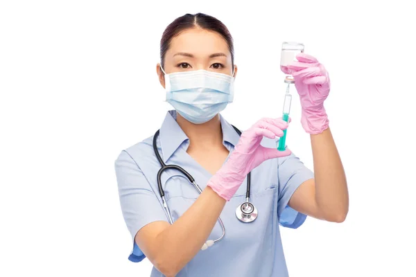 Asiatische Krankenschwester in Maske mit Medikamenten in Spritze — Stockfoto