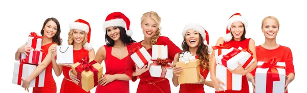Boldog nők télapó kalapban karácsonyi ajándékokkal — Stock Fotó