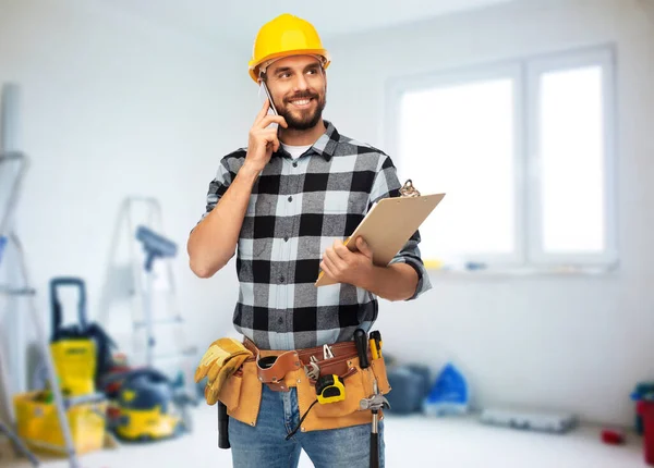 Happy builder with clipboard calling on smartphone — Stock Photo, Image