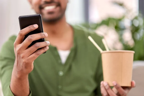 Homme indien avec téléphone manger à emporter nourriture à la maison — Photo