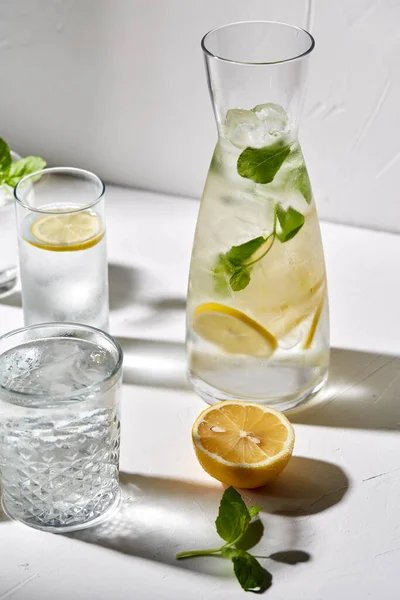 Bicchieri con acqua al limone e menta piperita in tavola — Foto Stock