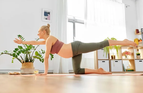 Glücklich schwangere Frau beim Yoga-Tisch posieren zu Hause — Stockfoto