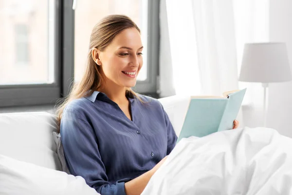 Mujer joven leyendo libro en la cama en casa —  Fotos de Stock