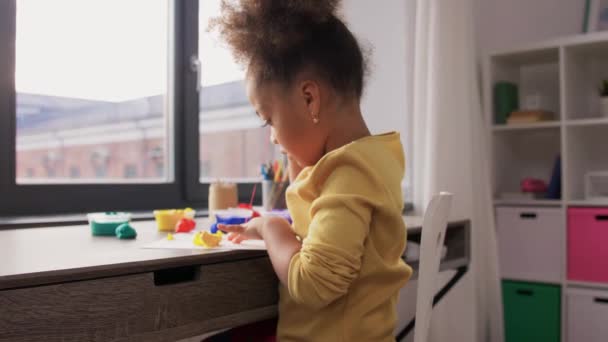 Маленькая девочка с моделью глины играет дома — стоковое видео