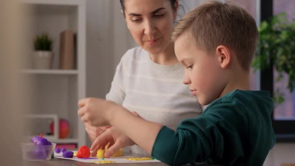 Мать и сын играют в модели глины дома — стоковое видео