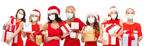 Mujeres felices en máscaras médicas con regalos de Navidad —  Fotos de Stock