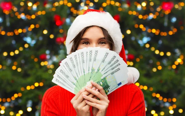Mujer feliz en sombrero de santa con dinero en Navidad —  Fotos de Stock