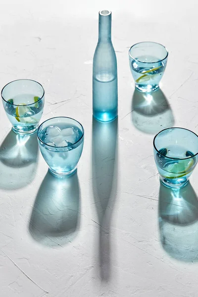 Glas med vatten och citroner på vit bakgrund — Stockfoto