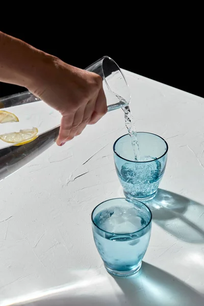 将水倒入装有柠檬和冰块的玻璃杯 — 图库照片