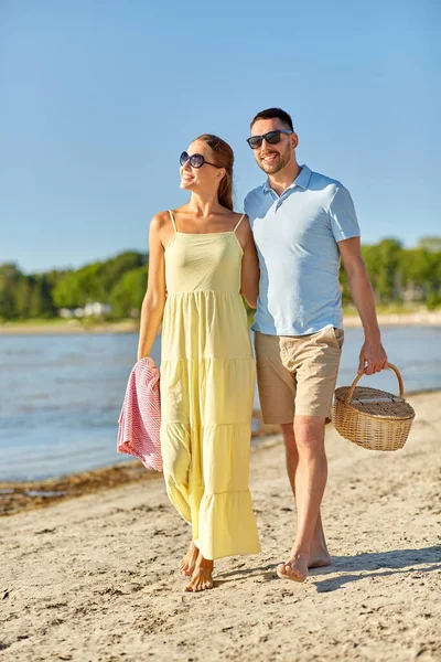 Lyckligt par med picknickkorg promenader på stranden — Stockfoto