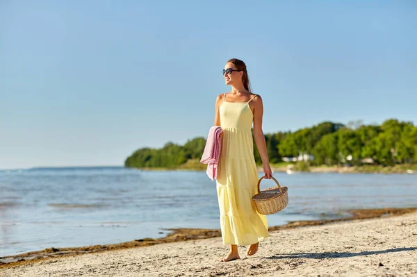 Lycklig kvinna med picknick korg promenader längs stranden — Stockfoto