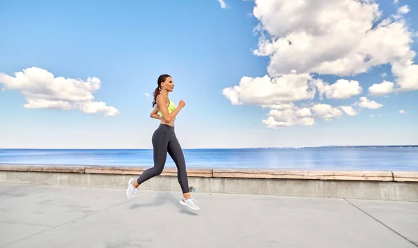 Junge Frau läuft entlang der Seepromenade — Stockfoto