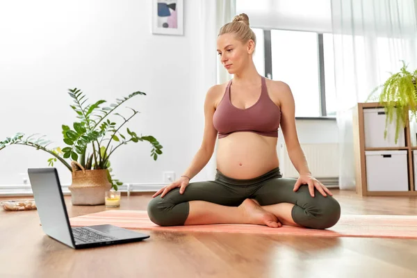 Pregnant woman with laptop doing yoga at home — Stock Photo, Image