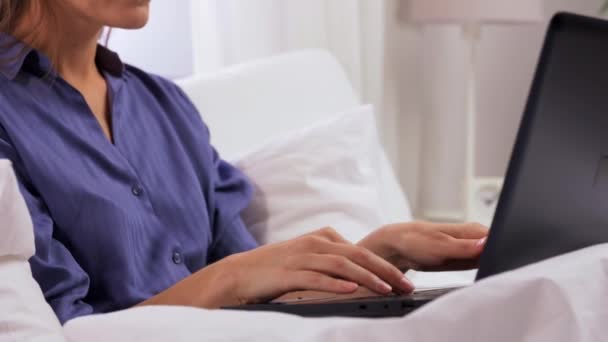 Wanita muda dengan laptop dan kertas di tempat tidur di rumah — Stok Video