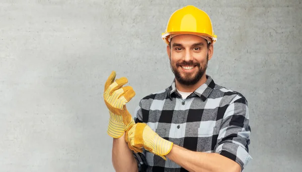 Glücklicher männlicher Arbeiter oder Bauarbeiter mit Helm und Handschuhen — Stockfoto