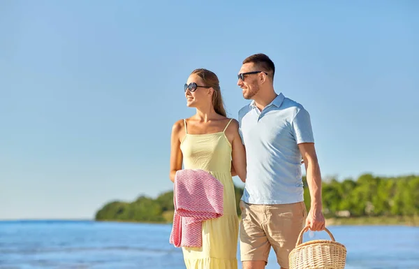 해변을 걷고 있는 피크닉 바구니를 든 행복 한 부부 — 스톡 사진