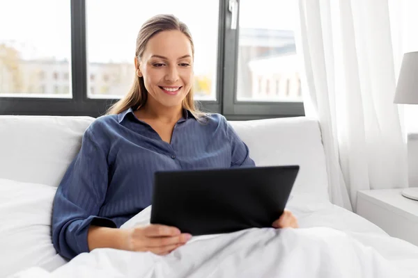 Jeune femme avec tablette PC dans le lit à la maison chambre — Photo