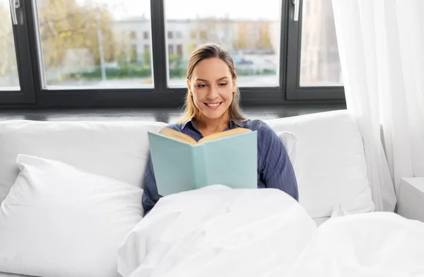 Jovem mulher ler livro na cama em casa — Fotografia de Stock