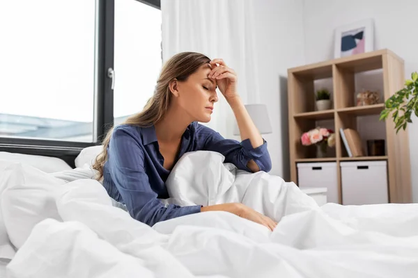 Ospalá nebo stresovaná žena sedí doma v posteli — Stock fotografie