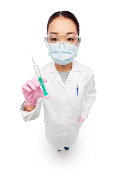 Asiatico femmina medico in maschera con siringa — Foto Stock
