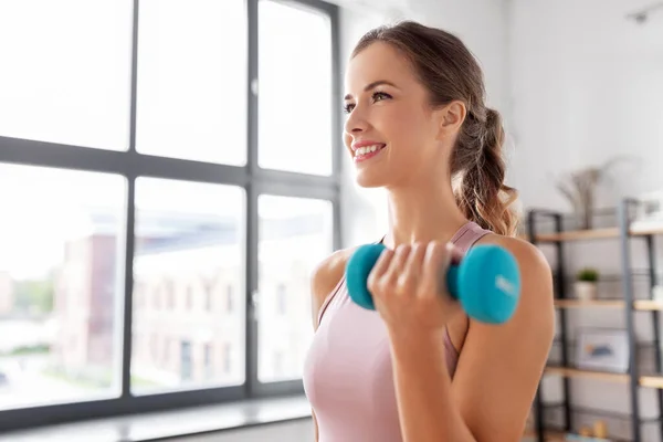 Sonriente joven con mancuernas ejercitándose en casa — Foto de Stock