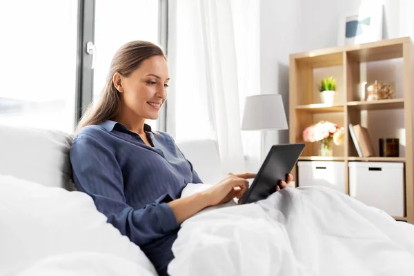 Jeune femme avec tablette PC dans le lit à la maison chambre — Photo