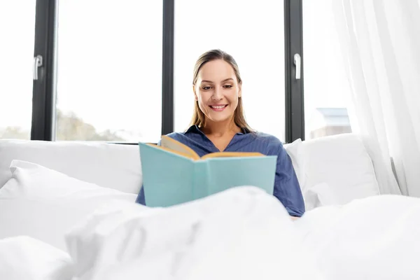 Jovem mulher ler livro na cama em casa — Fotografia de Stock