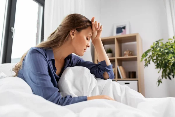 Mujer somnolienta o estresada sentada en la cama en casa —  Fotos de Stock