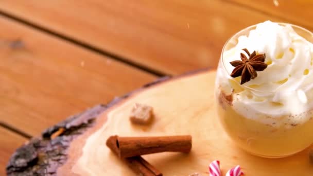 Vasos de ponche de huevo, bastones de caramelo y especias sobre madera — Vídeos de Stock