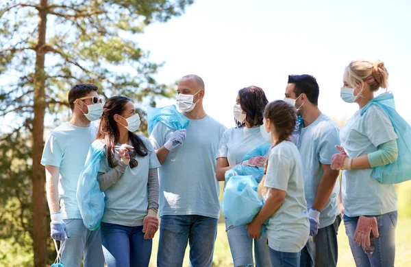 Voluntários em máscaras com sacos de lixo falando — Fotografia de Stock
