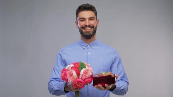 Szczęśliwy młody człowiek z bukietem kwiatów i pudełka prezentów — Wideo stockowe