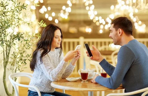 Szczęśliwa para ze smartfonami picie herbaty w kawiarni — Zdjęcie stockowe