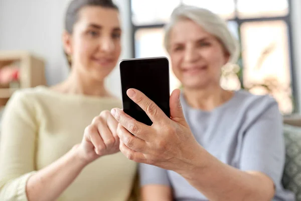 Dochter en senior moeder met smartphone thuis — Stockfoto