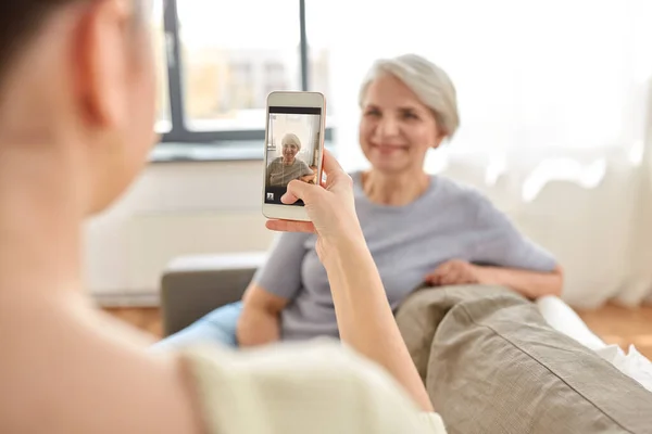 Dorosła córka fotografuje starszą matkę w domu — Zdjęcie stockowe