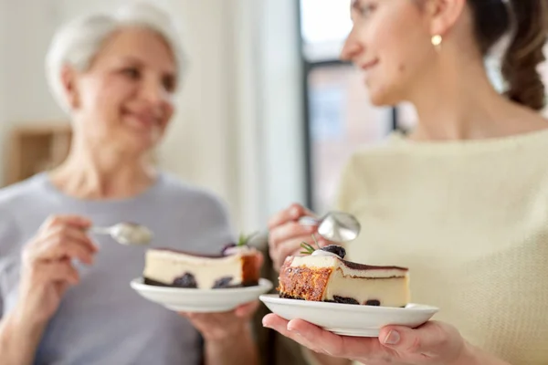 Стара мати і доросла дочка їдять торт вдома — стокове фото
