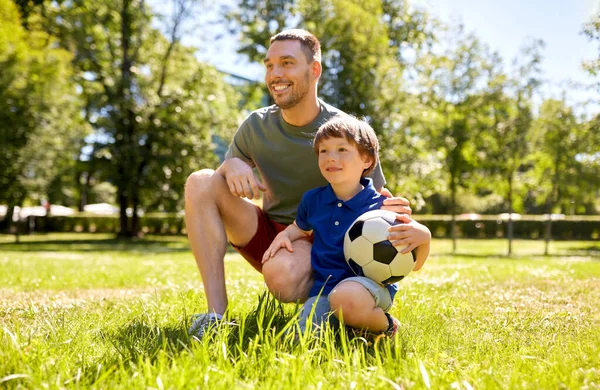 Отец и маленький сын с футбольным мячом в парке — стоковое фото
